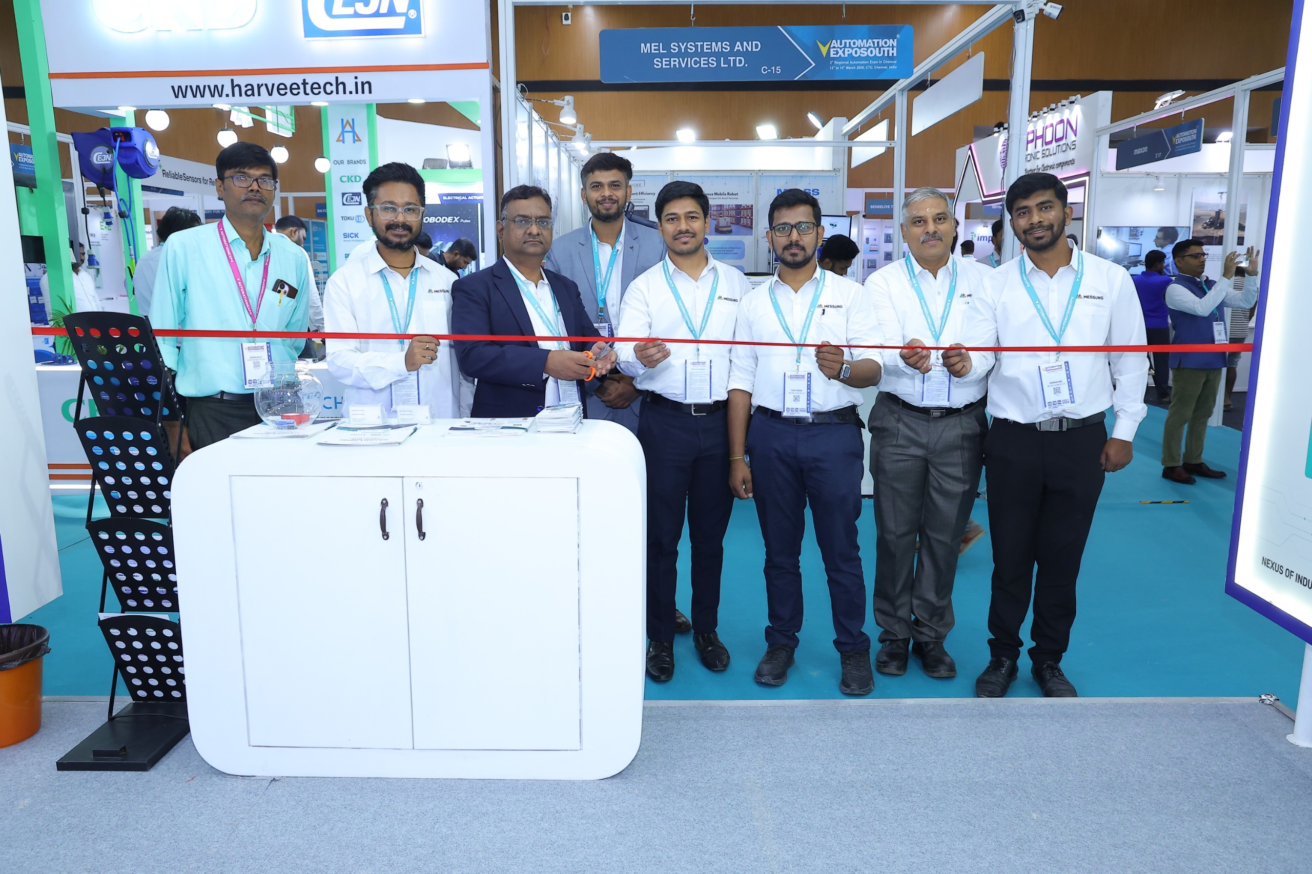 Team members performing ribbon cutting ceremony at industrial automation exhibition booth